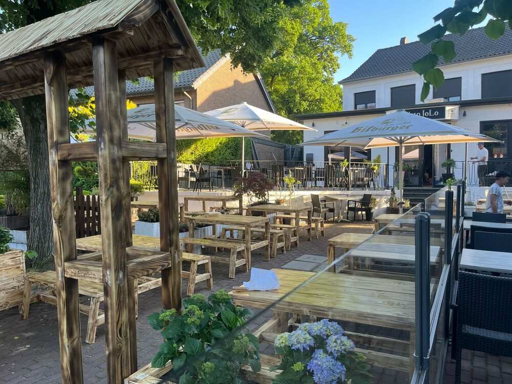 Außenterrasse mit Holzbänken unter einer alten Pergola